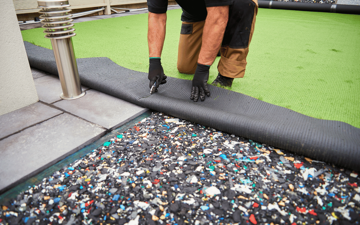 Operario ajustando juntas de césped artificial durante proceso de instalación
